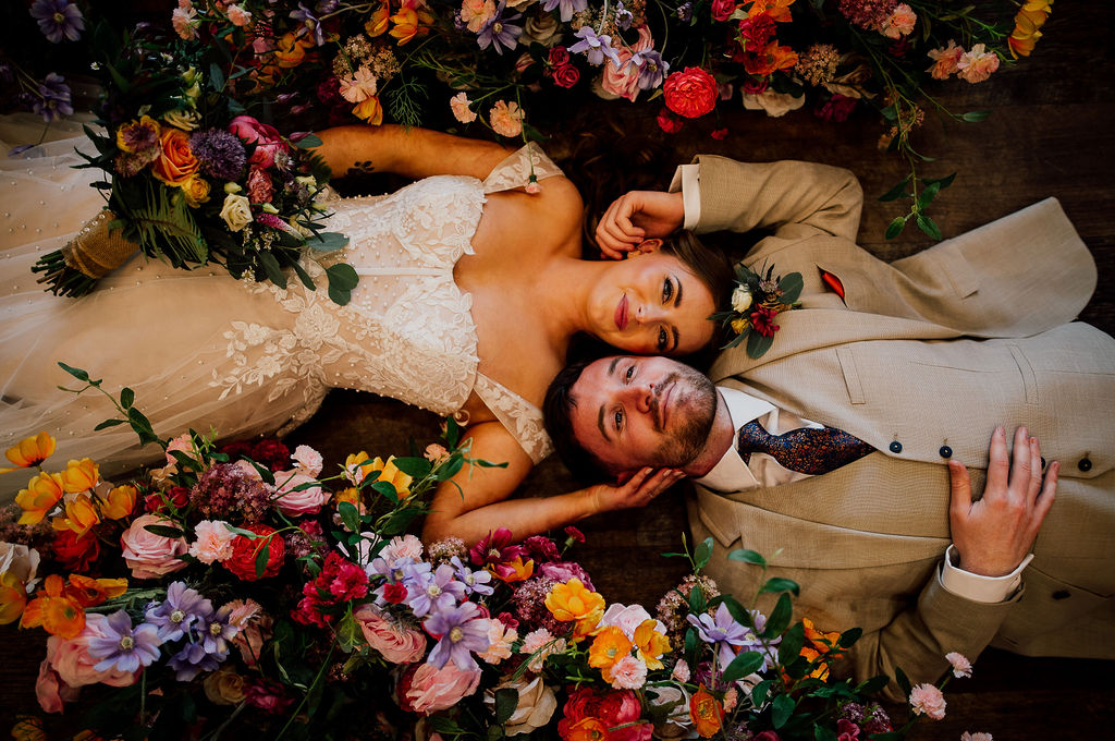 West Midlands wedding venue. Bride & Groom lying on a wooden floor surrounded by flowers. Copyrightdearestlove 338